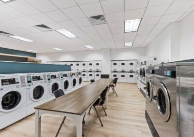 View of UC's 24-hour free laundry facility with modern machines, including washer, dryers, and folding tables.