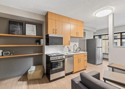 View of convertible apartment's full kitchen, living space, and full fridge.